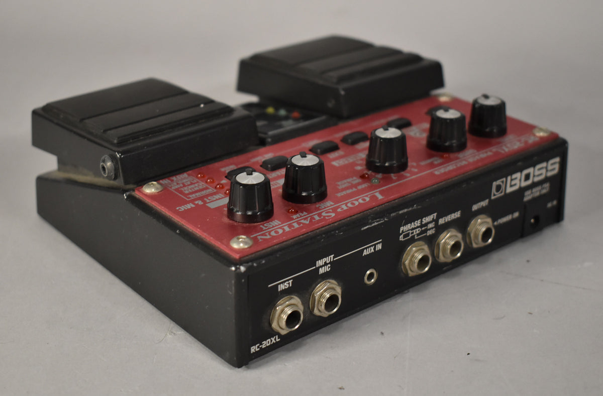 A red and black loop station pedal, viewed from the right, showing two foot pedals, four control knobs, and multiple input/output jacks.