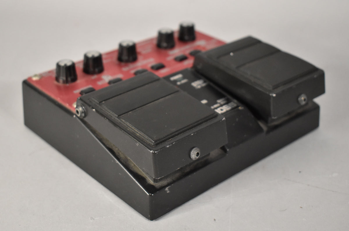 A used red and black effect pedal, viewed from the right, showing two black foot pedals and four black control knobs.