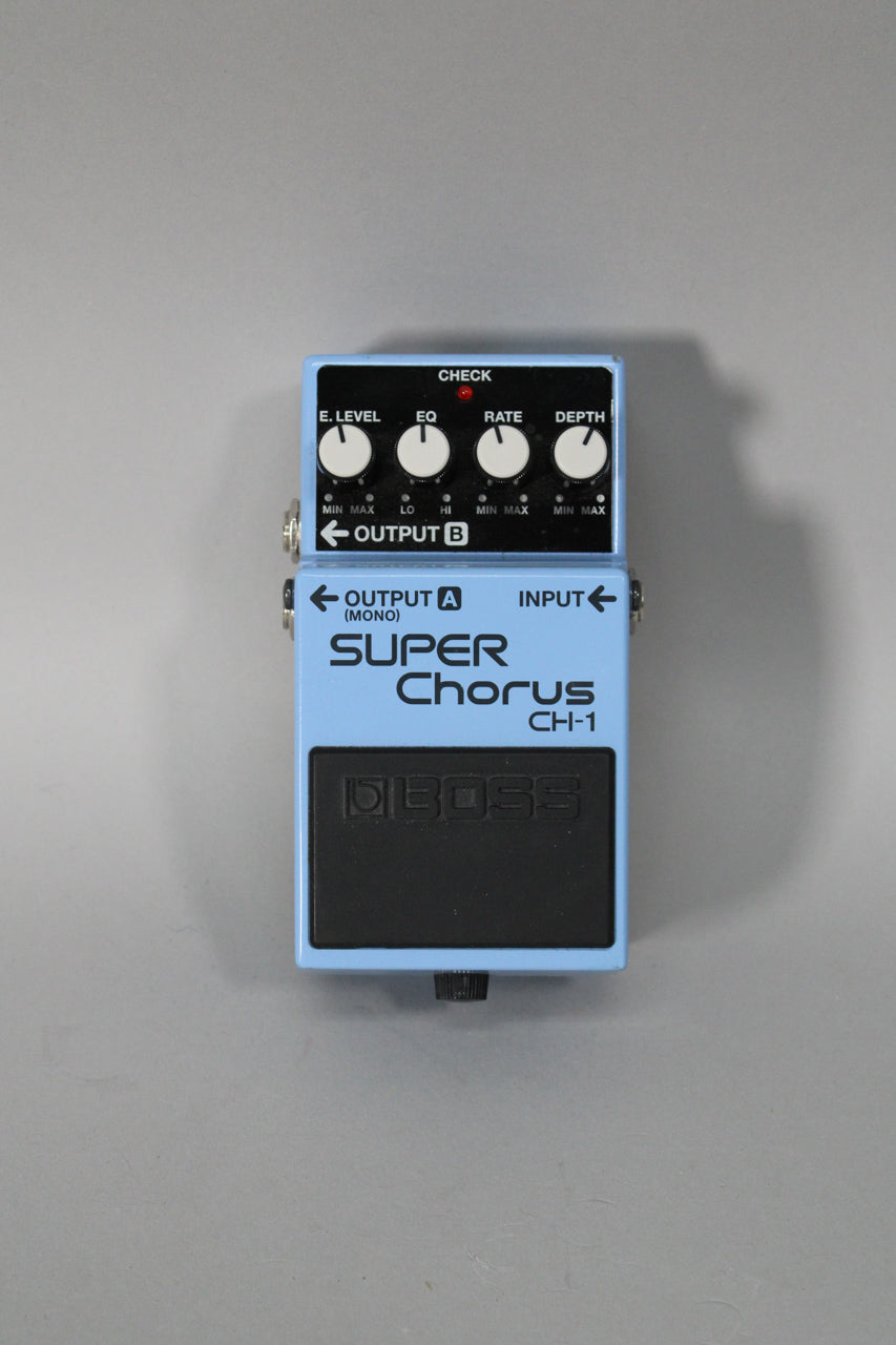Top-down view of a light blue pedal with a black footswitch, four white control knobs, and a red indicator light.