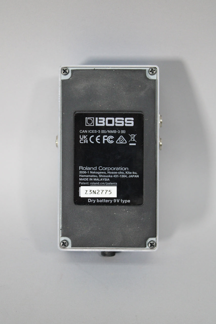 The pedal's gray underside is visible, with a black rectangular label showing text and a serial number.