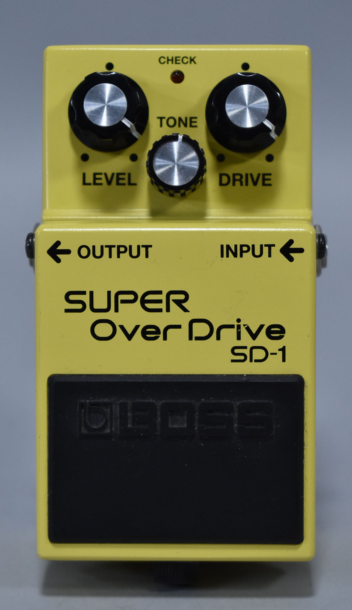 A bright yellow pedal with a black footswitch, three black knobs with silver tops, and a small red indicator light.