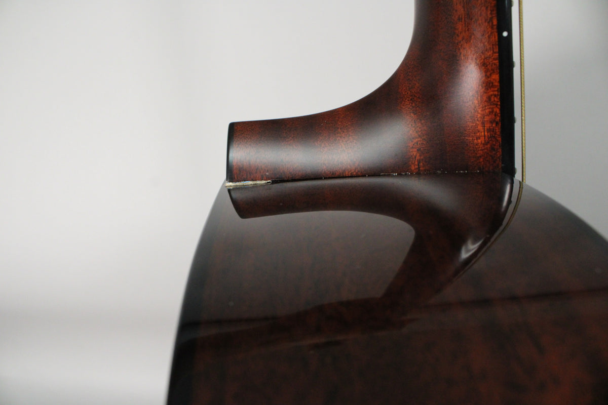 Close-up of the guitar's dark brown neck heel and body, showing a small chip in the finish where the neck meets the body.