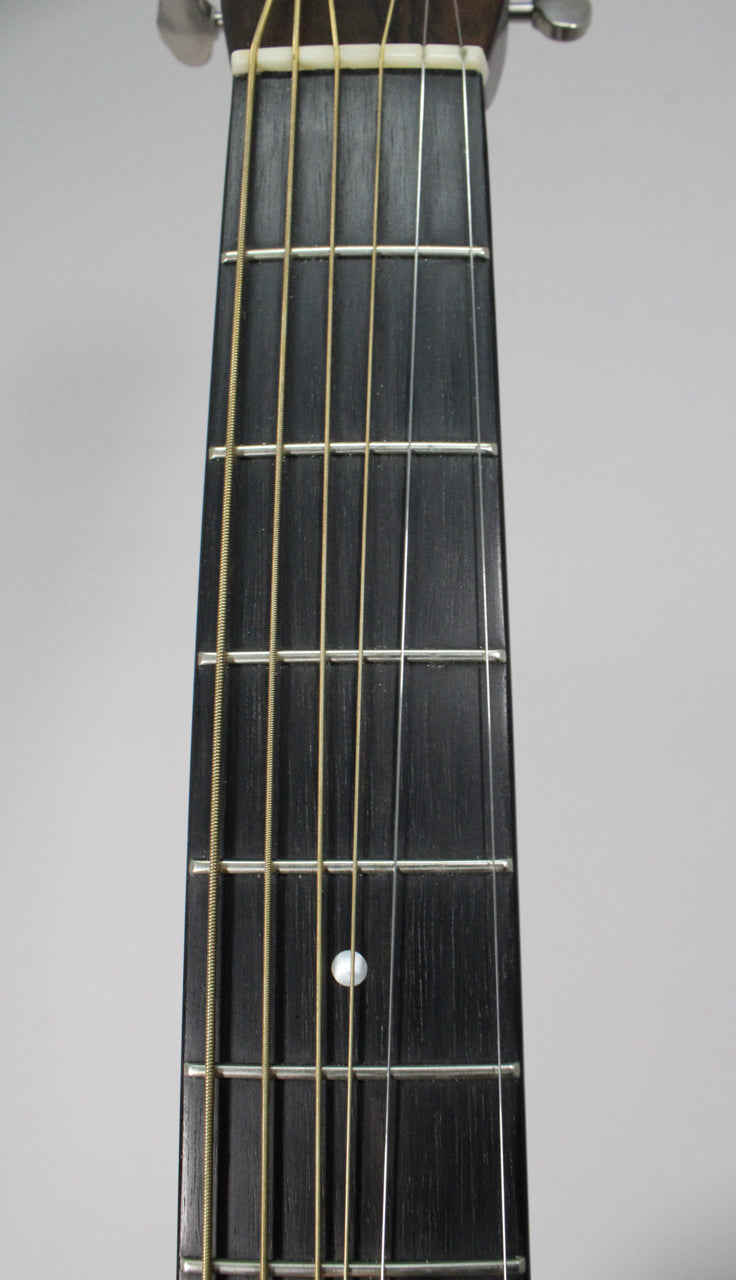 Close-up of the dark fretboard with light strings, showing a single mother-of-pearl dot inlay at the 7th fret.