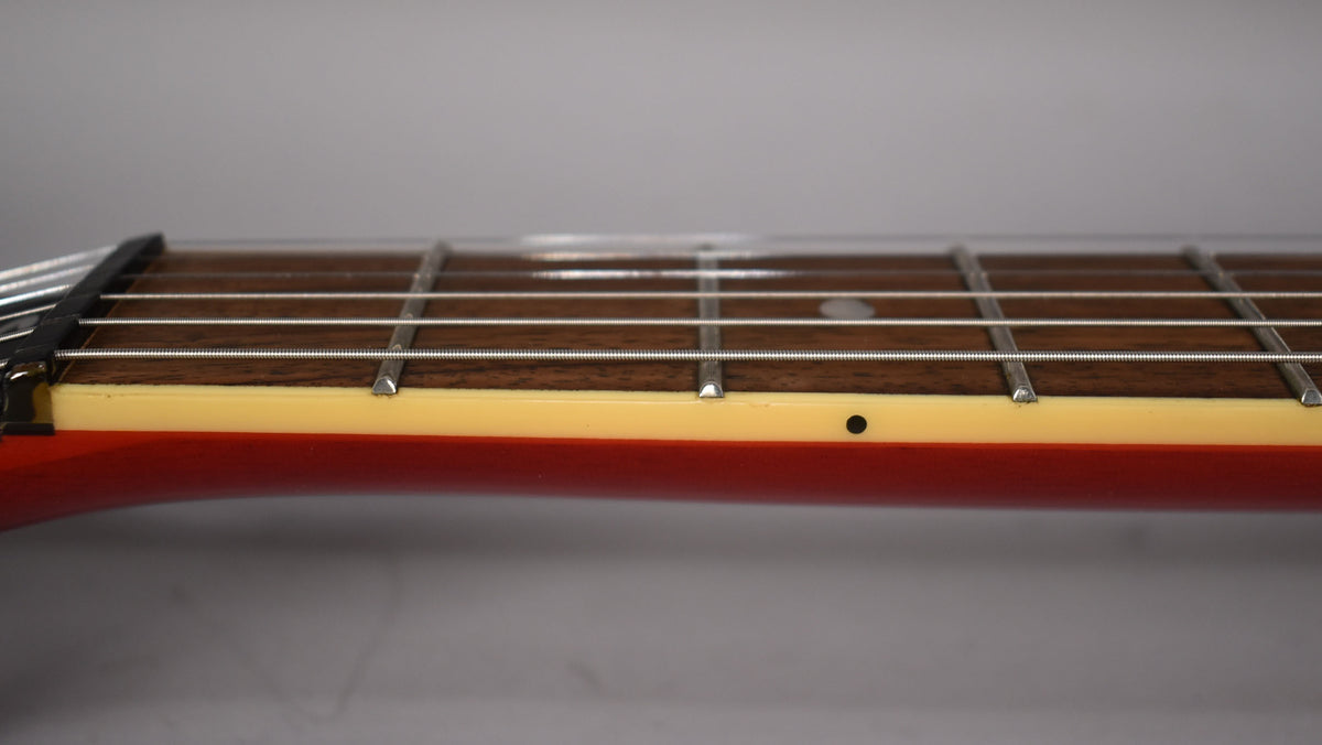 Close-up of the guitar's fretboard and neck, showing the dark wood, metal frets, and cream binding with black side dots.