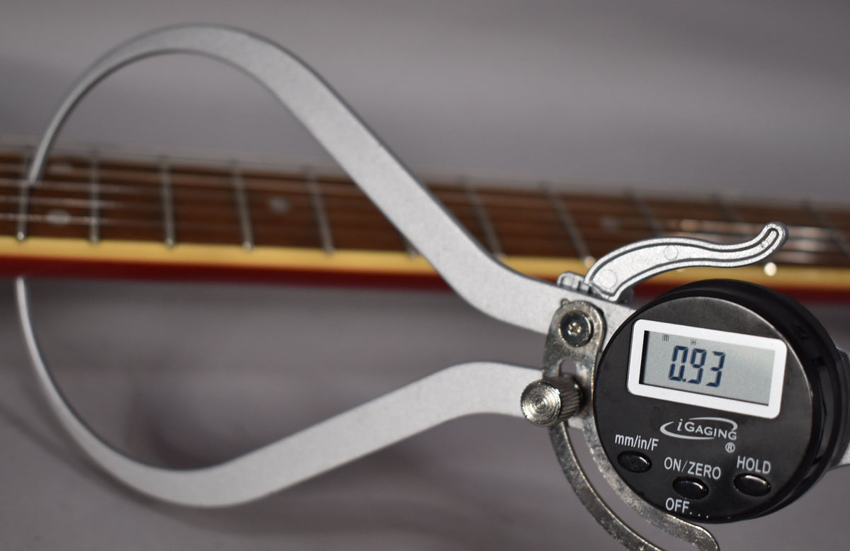 A digital caliper measures the guitar's neck thickness at 0.93 inches, with the cinnamon-finished fretboard visible behind it.