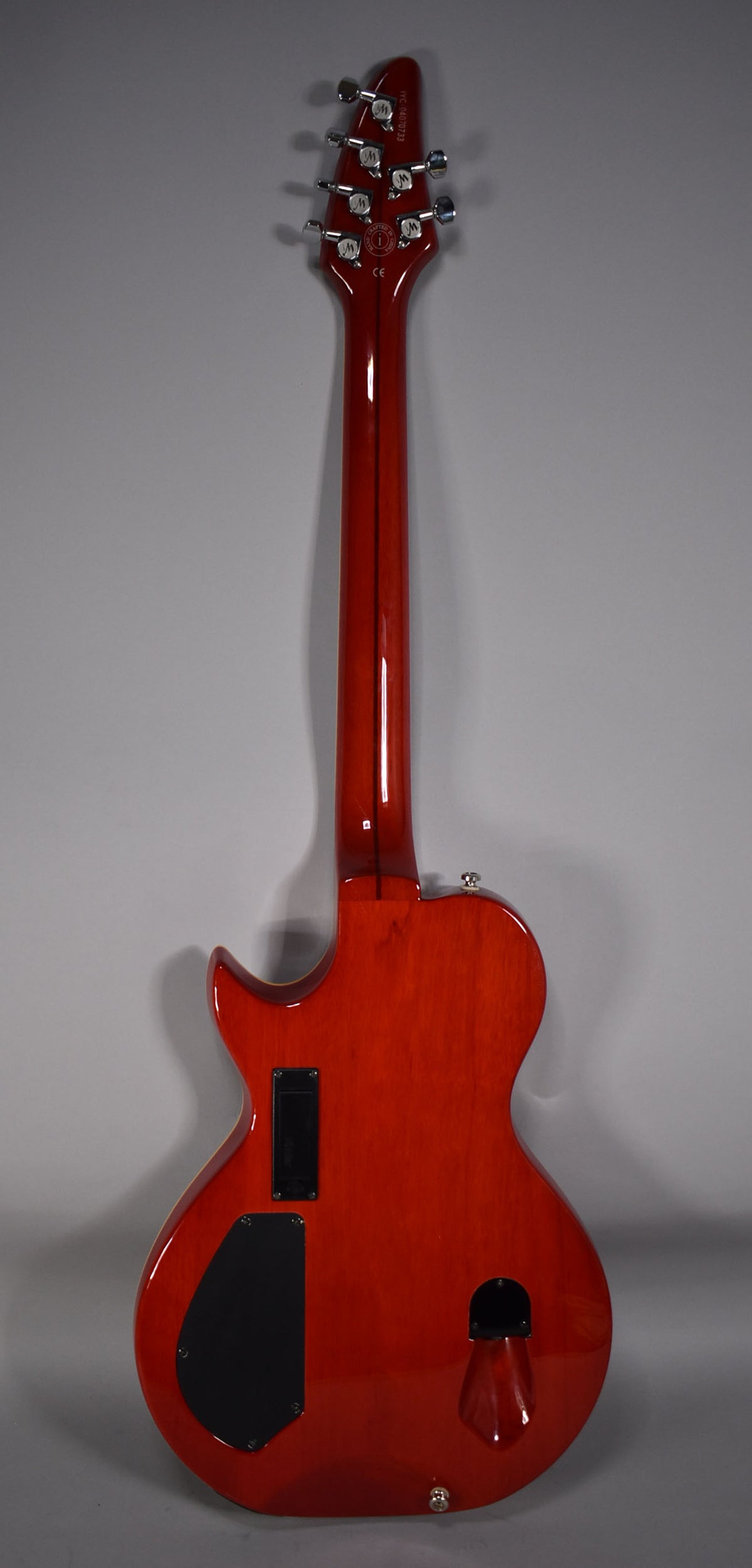 Full rear view of a glossy cinnamon guitar with a matching headstock, six chrome tuners, and three black control cavity covers.