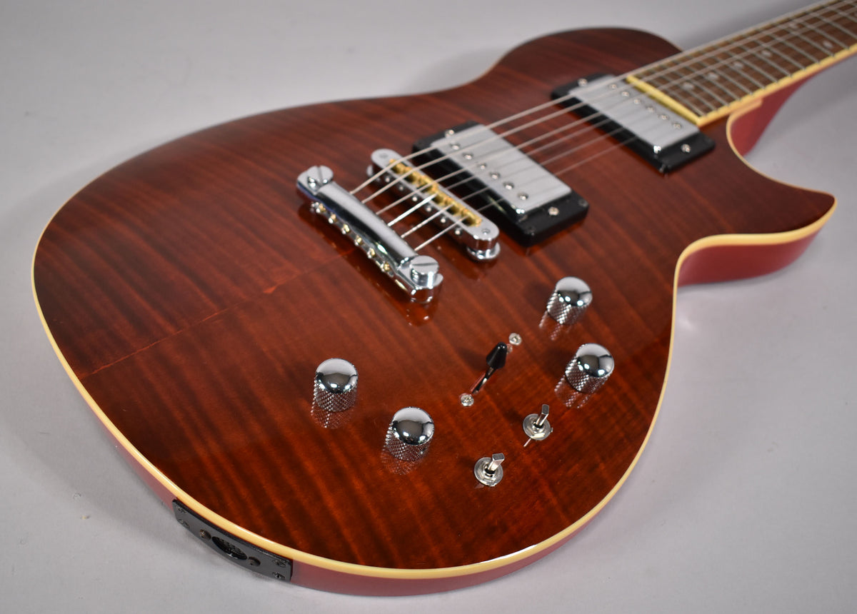 The cinnamon burst electric guitar body, with visible wood grain, has chrome hardware, four knurled knobs, and two toggle switches.