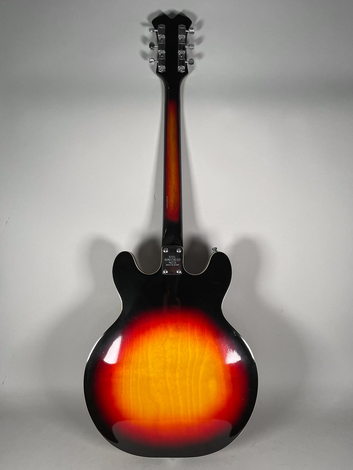 The back of a sunburst hollowbody electric guitar, showing the neck and headstock with six chrome tuners.