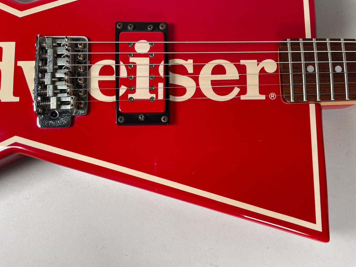 Close-up of the red guitar body with cream trim, showing the bridge, a single humbucker pickup, and part of the fretboard.