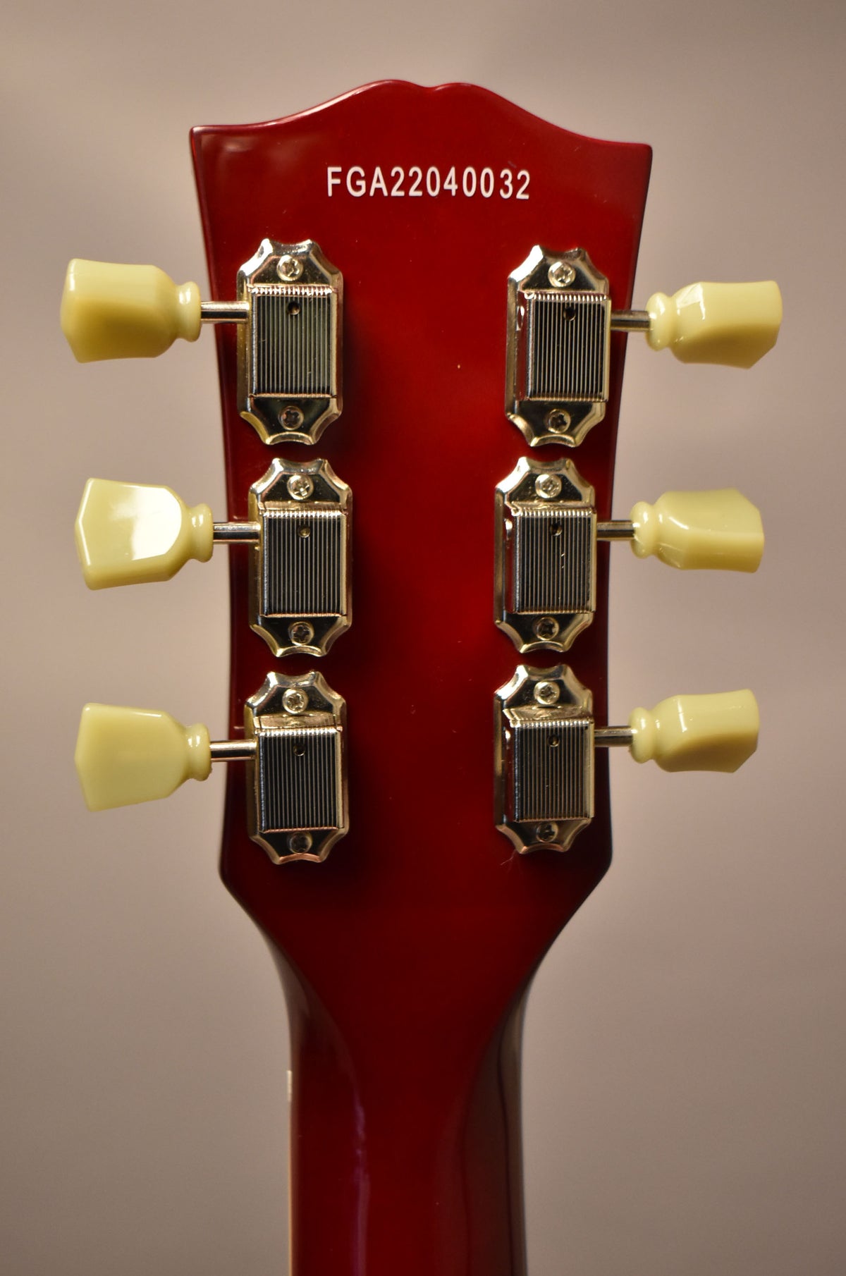Rear view of the cherry red headstock and neck, showing six chrome tuners with cream plastic buttons.