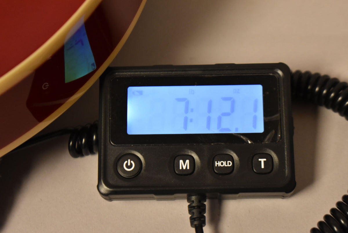 The cherry red guitar body with cream binding is partially visible next to a digital scale displaying "7:12.1 lb".