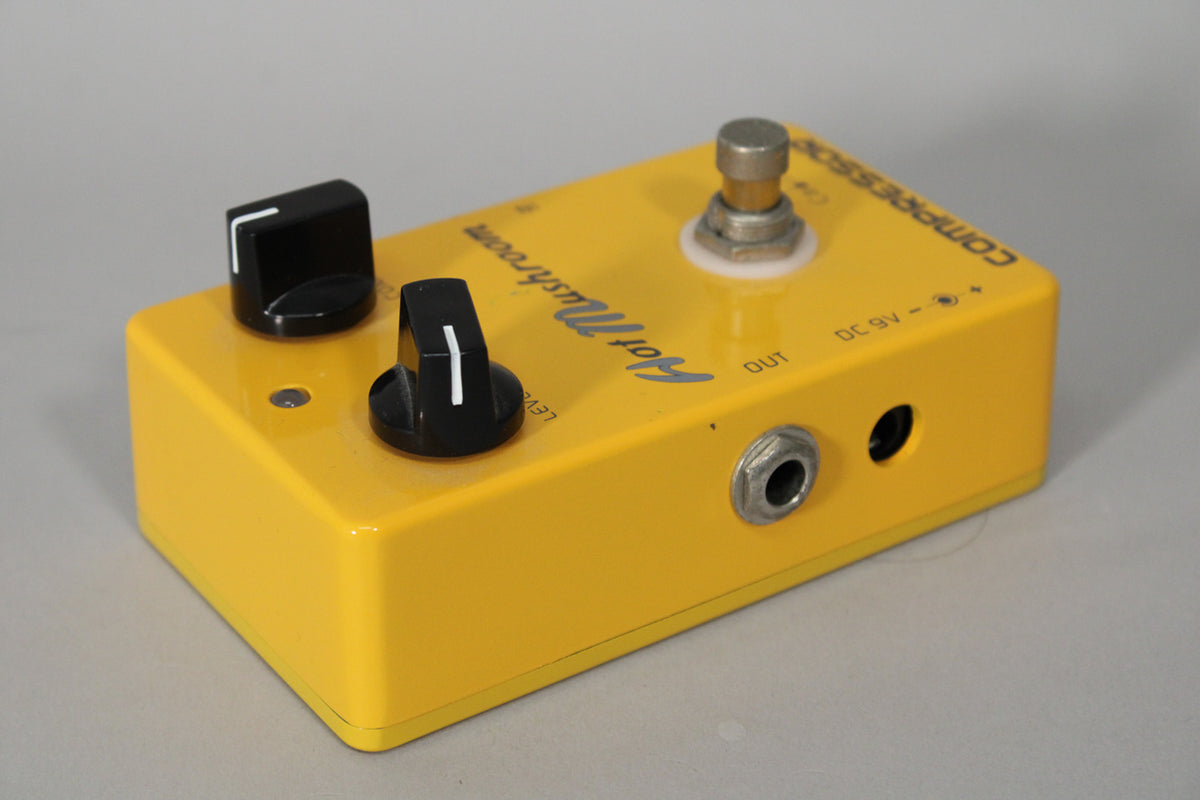 Yellow stompbox pedal, angled from the right, showing two black knobs, a footswitch, and two input jacks on the side.