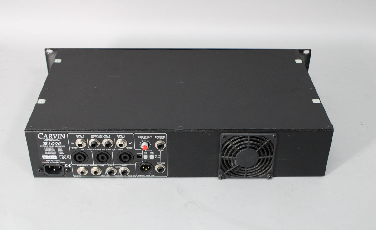 Rear view of a black bass amp head, showing a fan grill on the right and various input/output jacks and controls on the left.