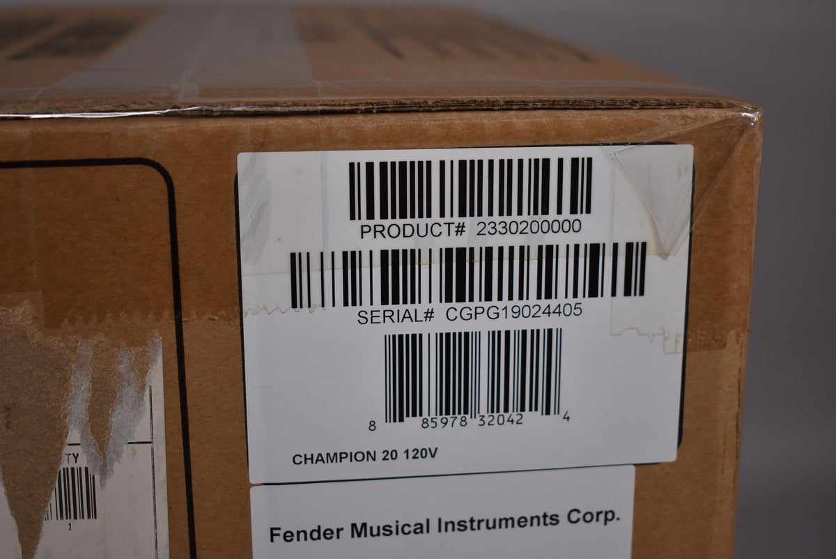 Close-up of a brown cardboard box with a white label showing product and serial numbers, partially covered by clear packing tape.