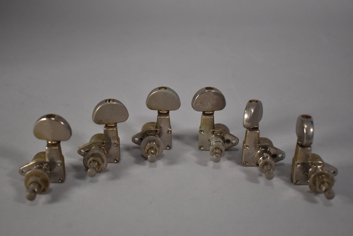 Six gold-finished tuners with D-shaped buttons are arranged in two rows, showing visible wear and tarnishing.
