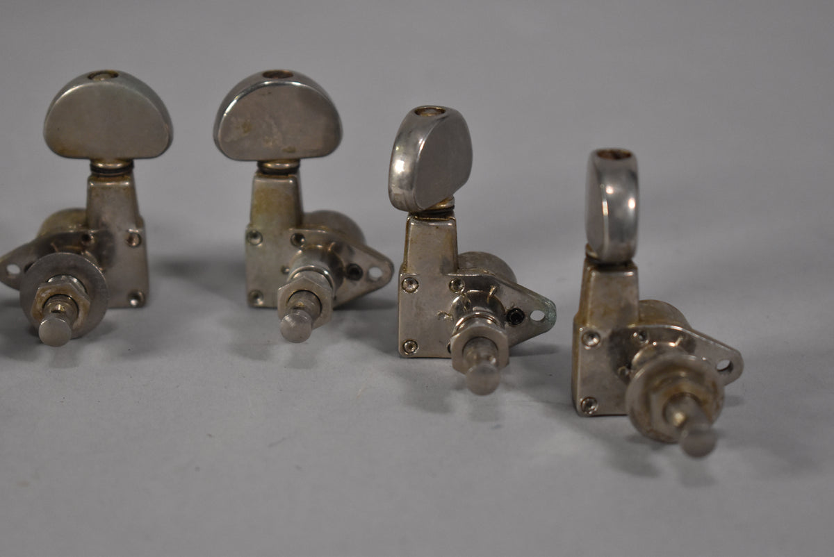 Four gold-finished tuners are angled right, showing the oval buttons and mounting plates with visible wear and tarnishing.