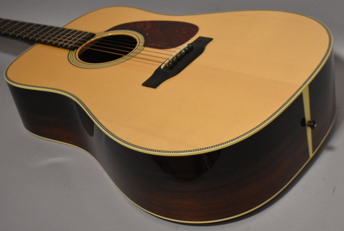 The acoustic guitar's light natural top and dark sides are angled, showing the soundhole, bridge, pickguard, and end pin.