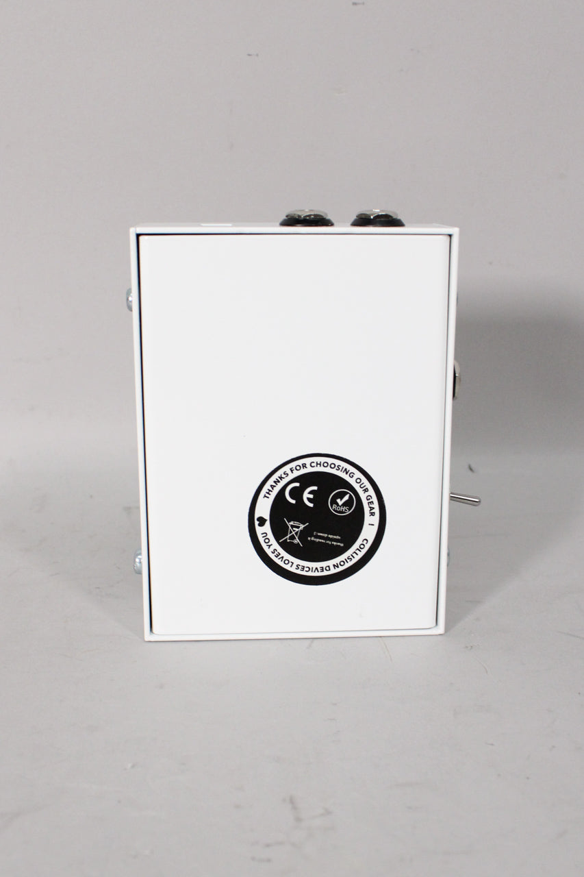 The white pedal is viewed from the back, showing a black circular sticker with regulatory marks and "Collision Devices Loves You".