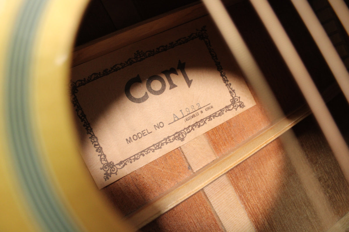 Close-up inside the soundhole, showing the light brown paper label with black text and decorative border, and internal bracing.
