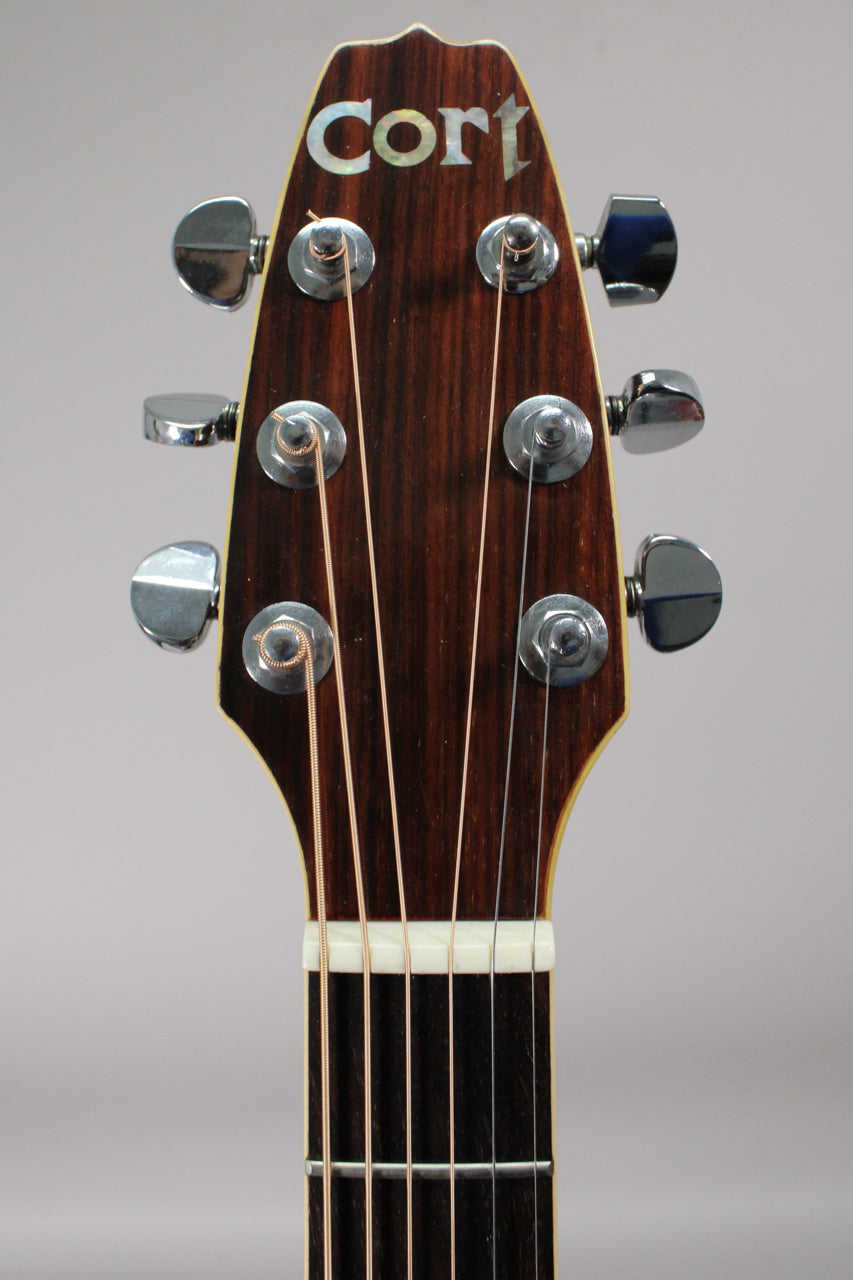 Close-up of the dark wood headstock with six chrome tuners, mother-of-pearl inlay, and a white nut.