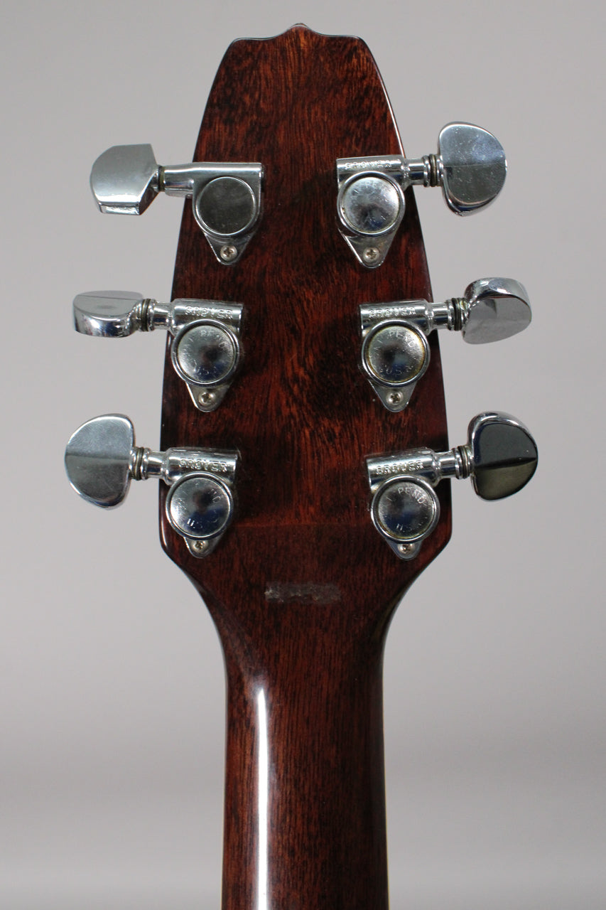 Rear view of the guitar's dark brown headstock and neck, showing six chrome tuners with some tarnishing and a worn patch on the neck.