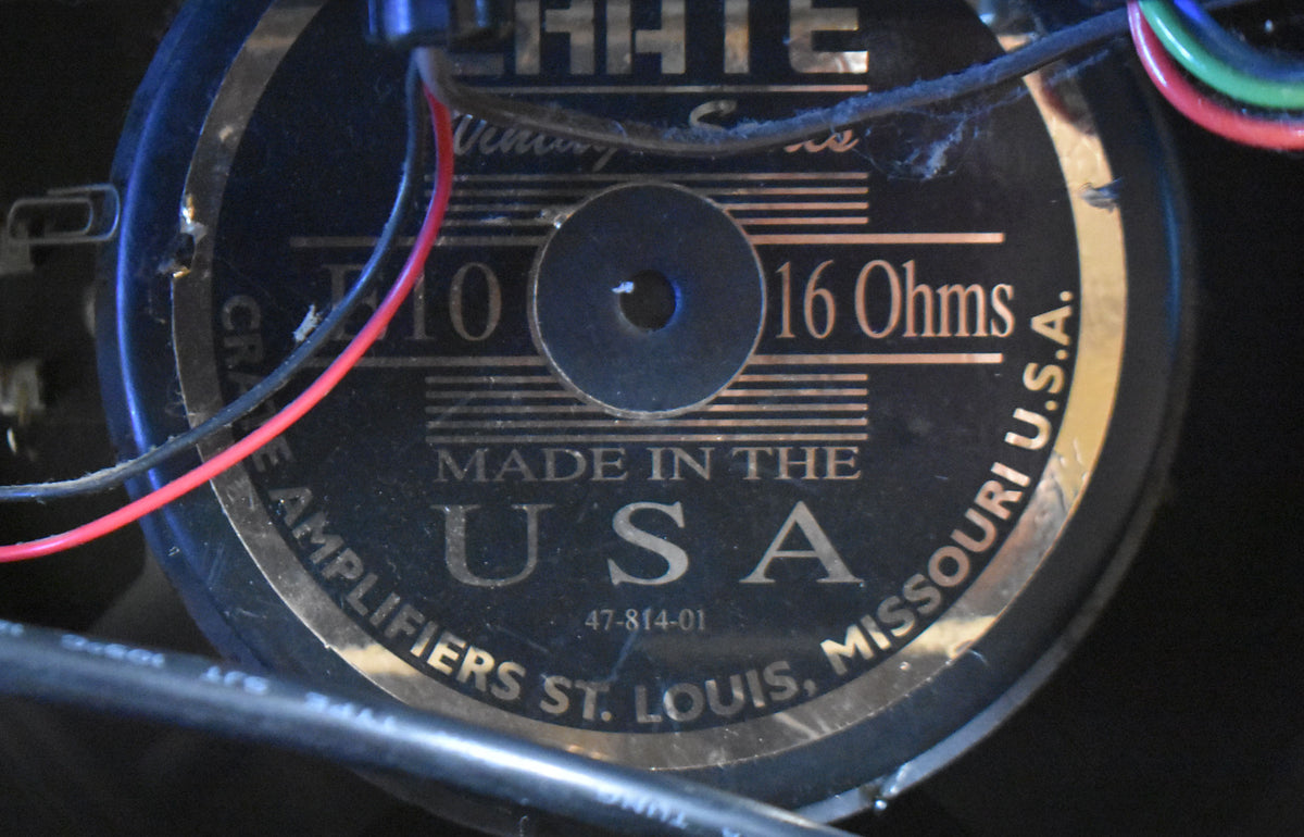 Close-up of the speaker's black and gold label, showing red and black wires, and some dust and wear.