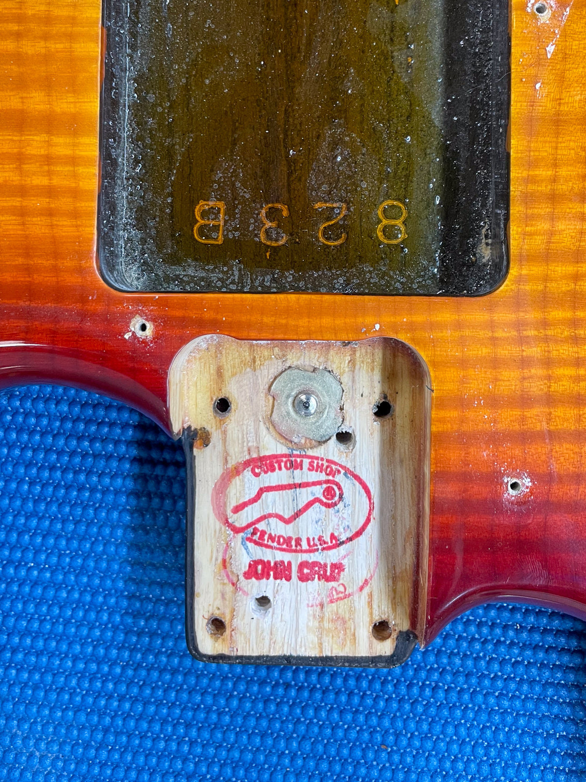 Close-up of the guitar's neck pocket and body, revealing a red "Custom Shop Fender U.S.A. John Cruz" stamp on the wood.