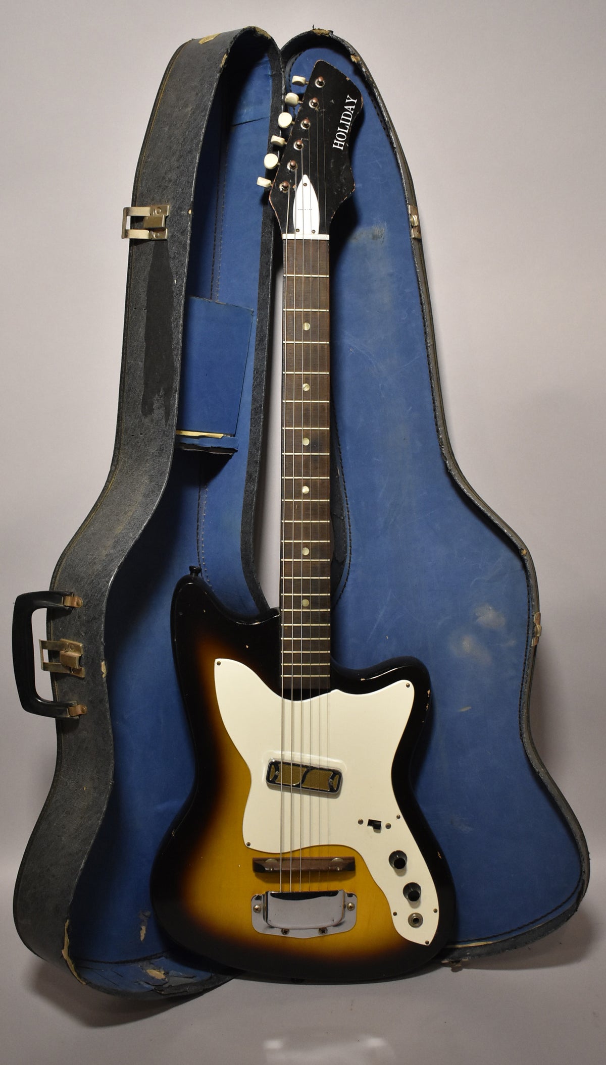 Full view of a sunburst electric guitar with a white pickguard, two pickups, and three control knobs, resting in a blue-lined case.