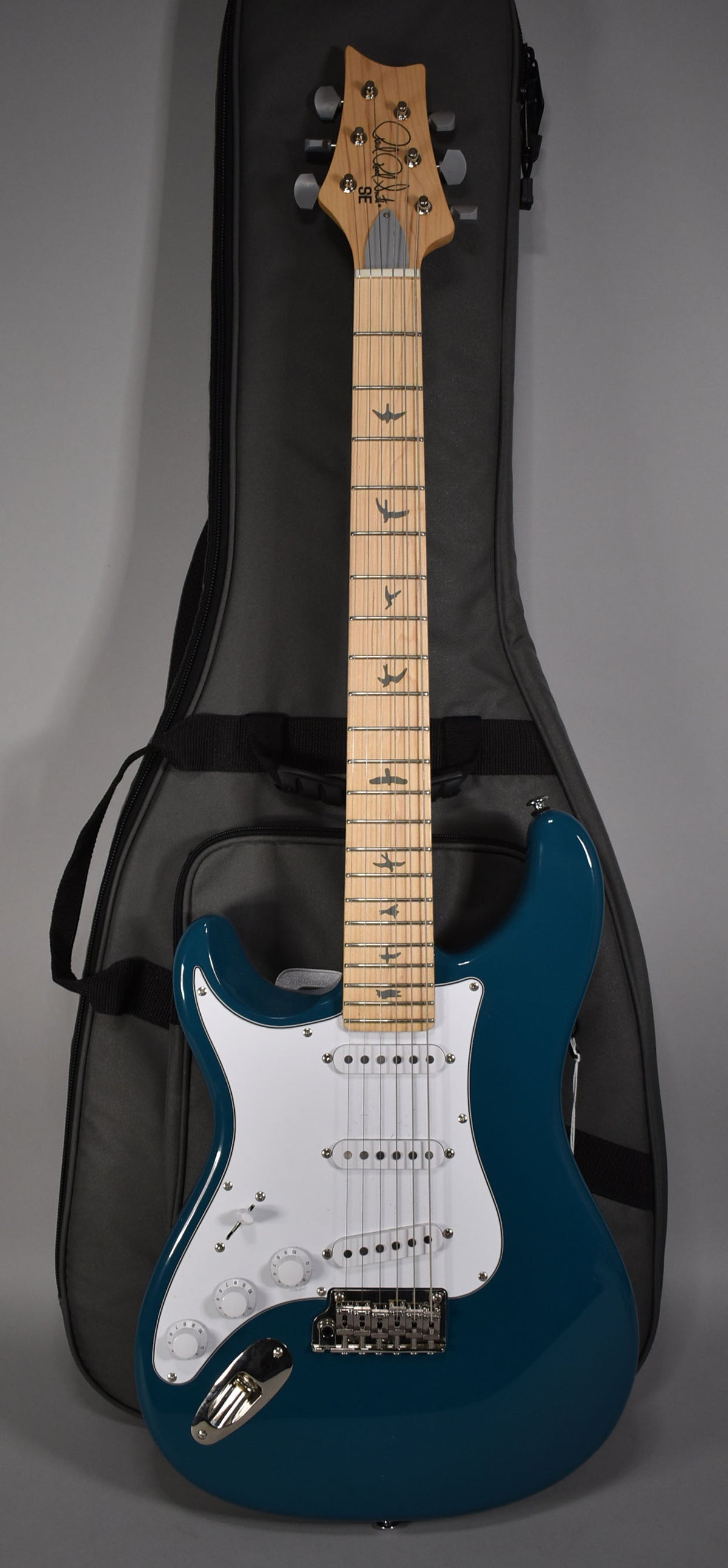 Full-length view of a glossy blue electric guitar with a white pickguard, three single-coil pickups, and a maple fretboard with bird inlays.