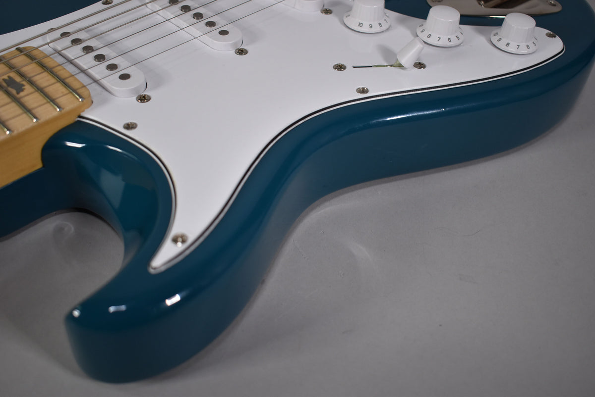 Close-up of the guitar's lower body, showing the glossy Nylon Blue finish, white pickguard, three white control knobs, and selector switch.