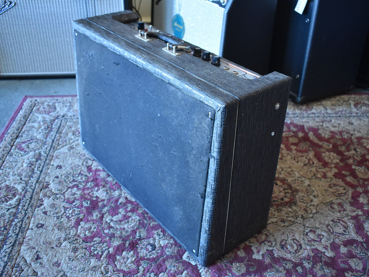 Dark gray amplifier with textured tolex and black grille cloth, viewed from the front-right, showing a metal handle and control knobs.