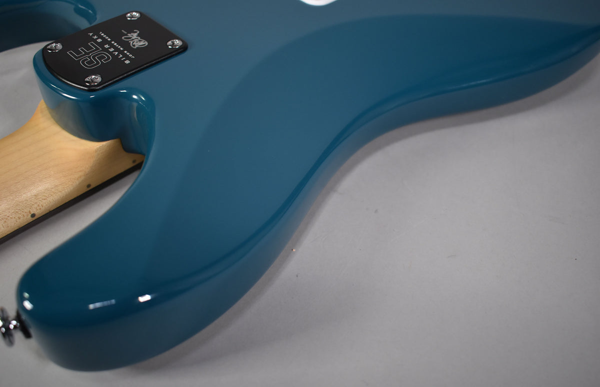 Close-up of the guitar's glossy blue lower bout and neck heel, revealing a black neck plate and chrome strap button.