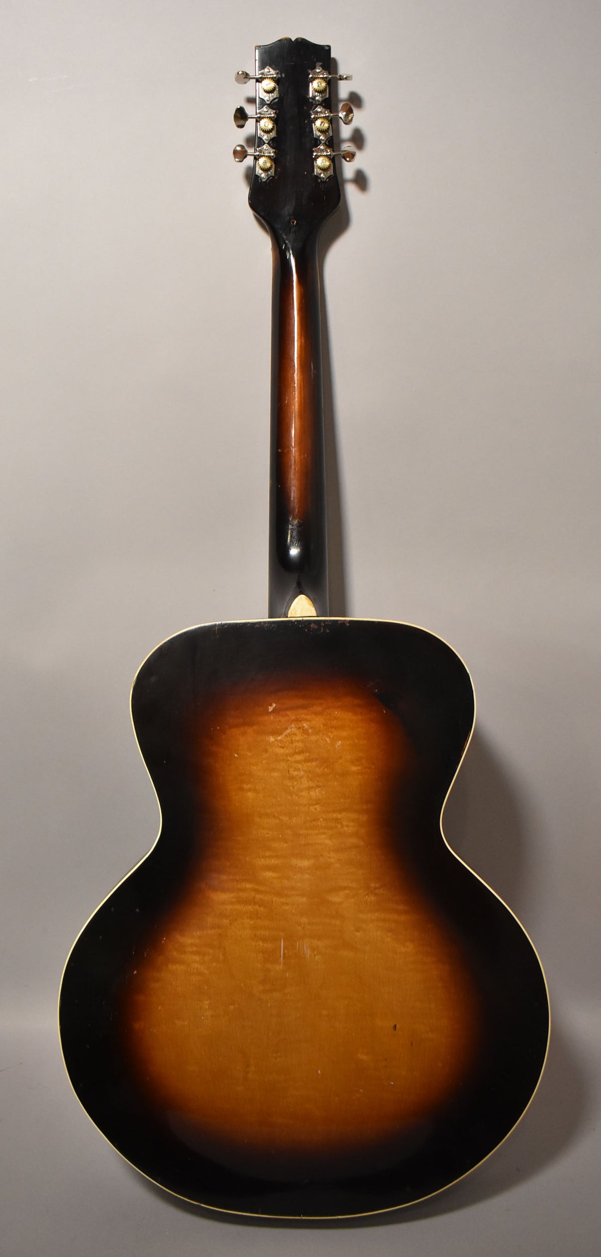 The guitar's back, neck, and headstock are visible, showing a sunburst finish with visible wear and checking.