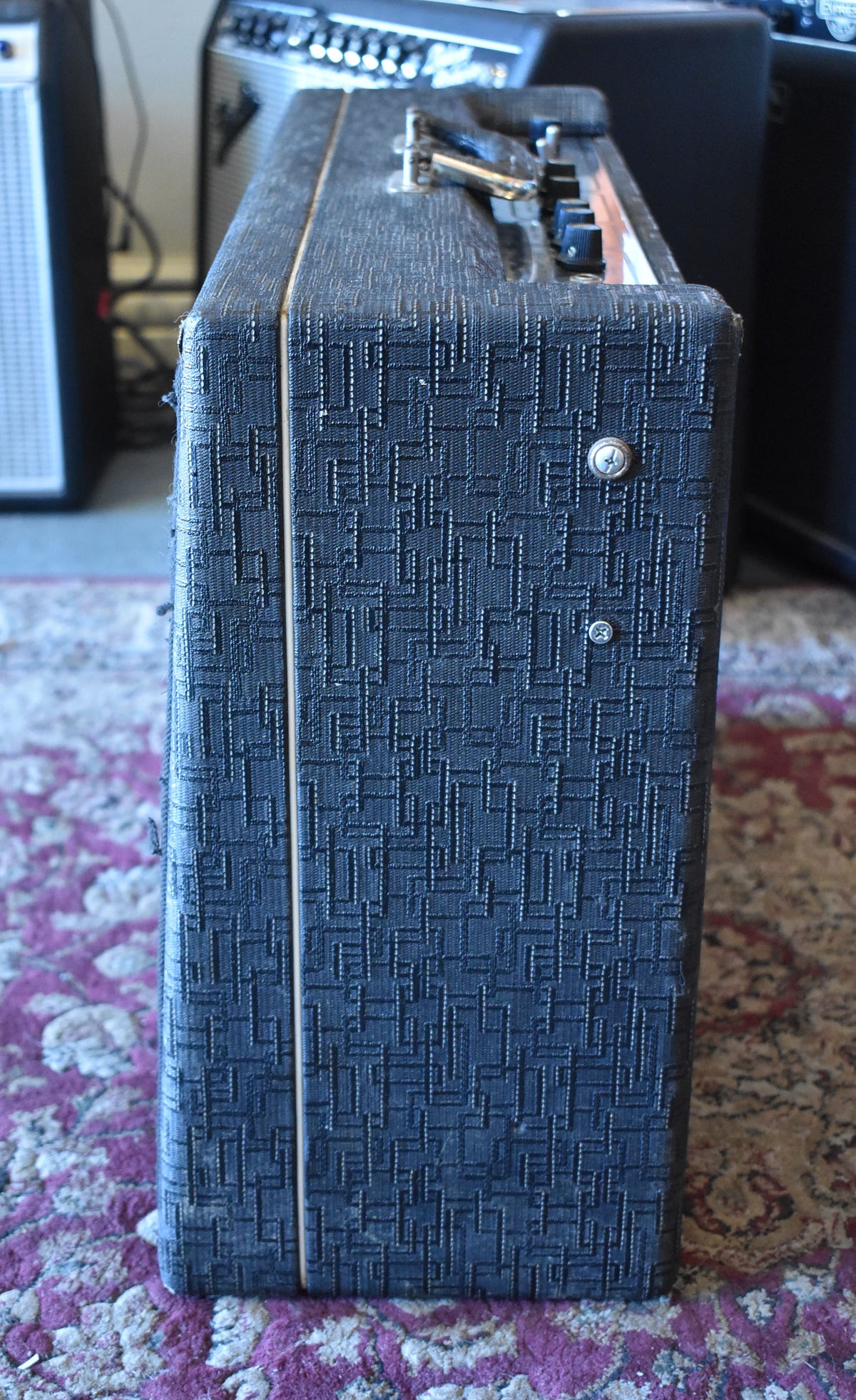 Right side of the dark blue textured amplifier, showing a thin cream stripe along the front edge and two silver screws.