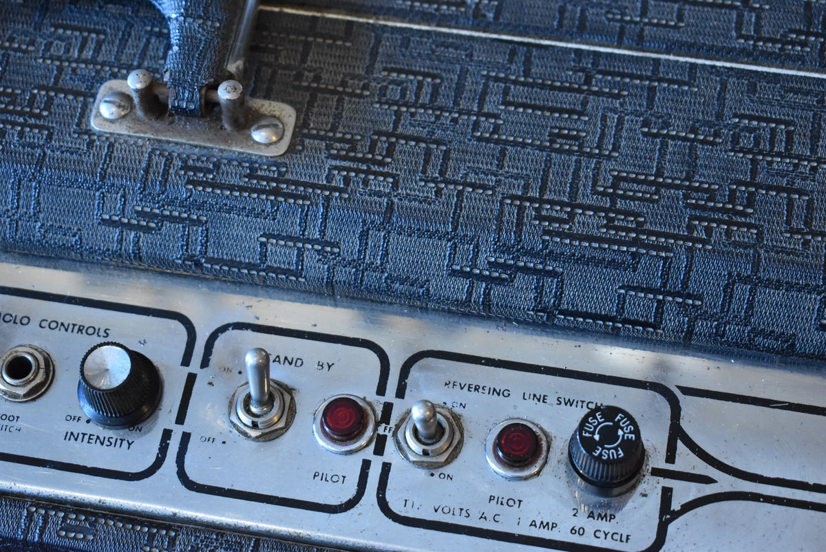 Close-up of the amp's top, showing a black patterned tolex, a silver control panel with toggle switches, red pilot lights, and a fuse cap.