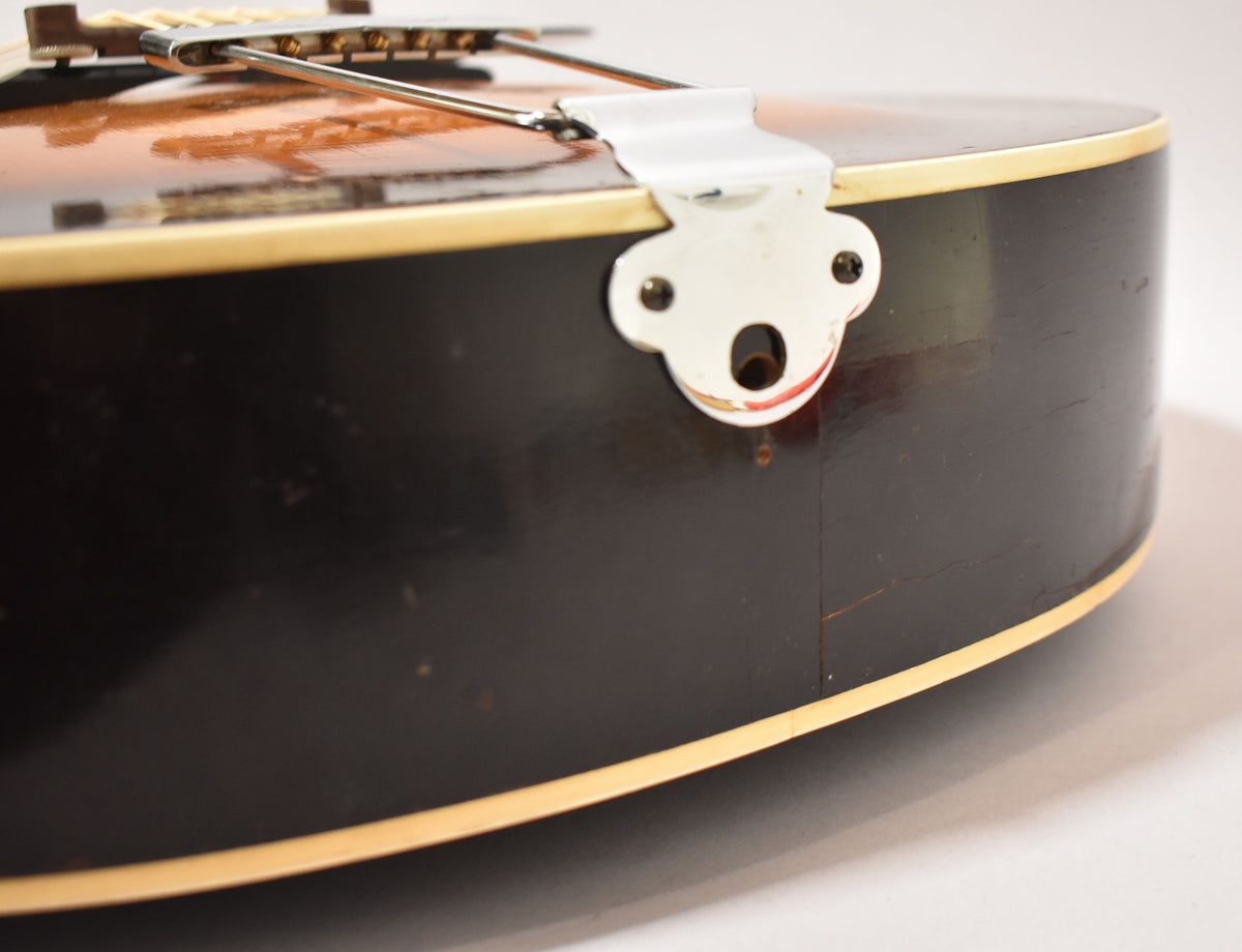 Close-up of the guitar's lower bout, showing the black sides with binding, chrome tailpiece, and visible finish checking and wear.