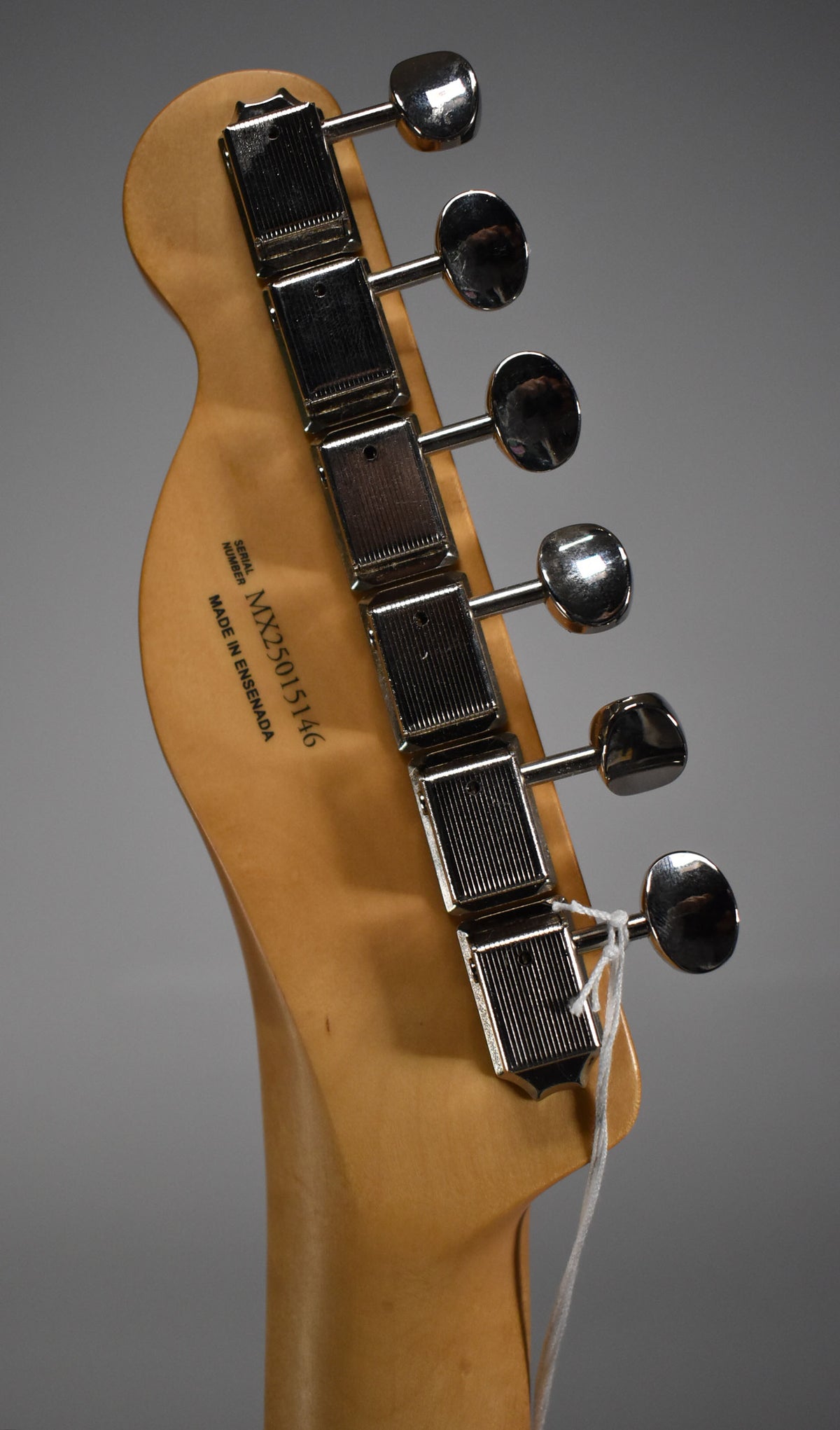 Close-up of the back of the headstock, showing six chrome tuners and a light wood finish with a faint string tied to the lowest tuner.