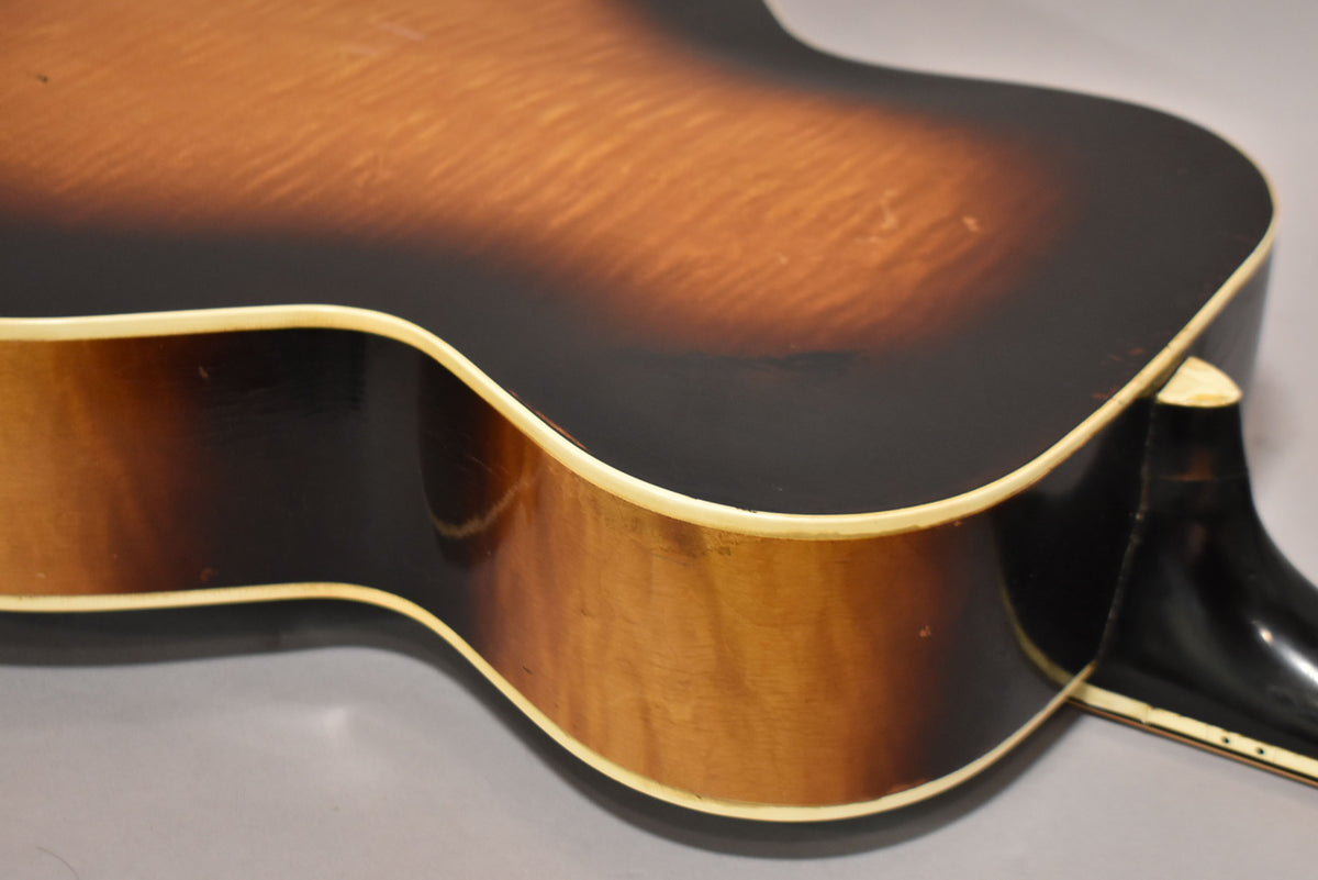 Close-up of the guitar's lower bout and cutaway, showing the dark sunburst finish, cream binding, and some finish checking.