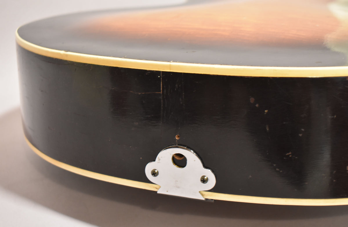 The guitar's lower bout, showing the dark sides with cream binding, a chrome tailpiece mount, and finish checking.