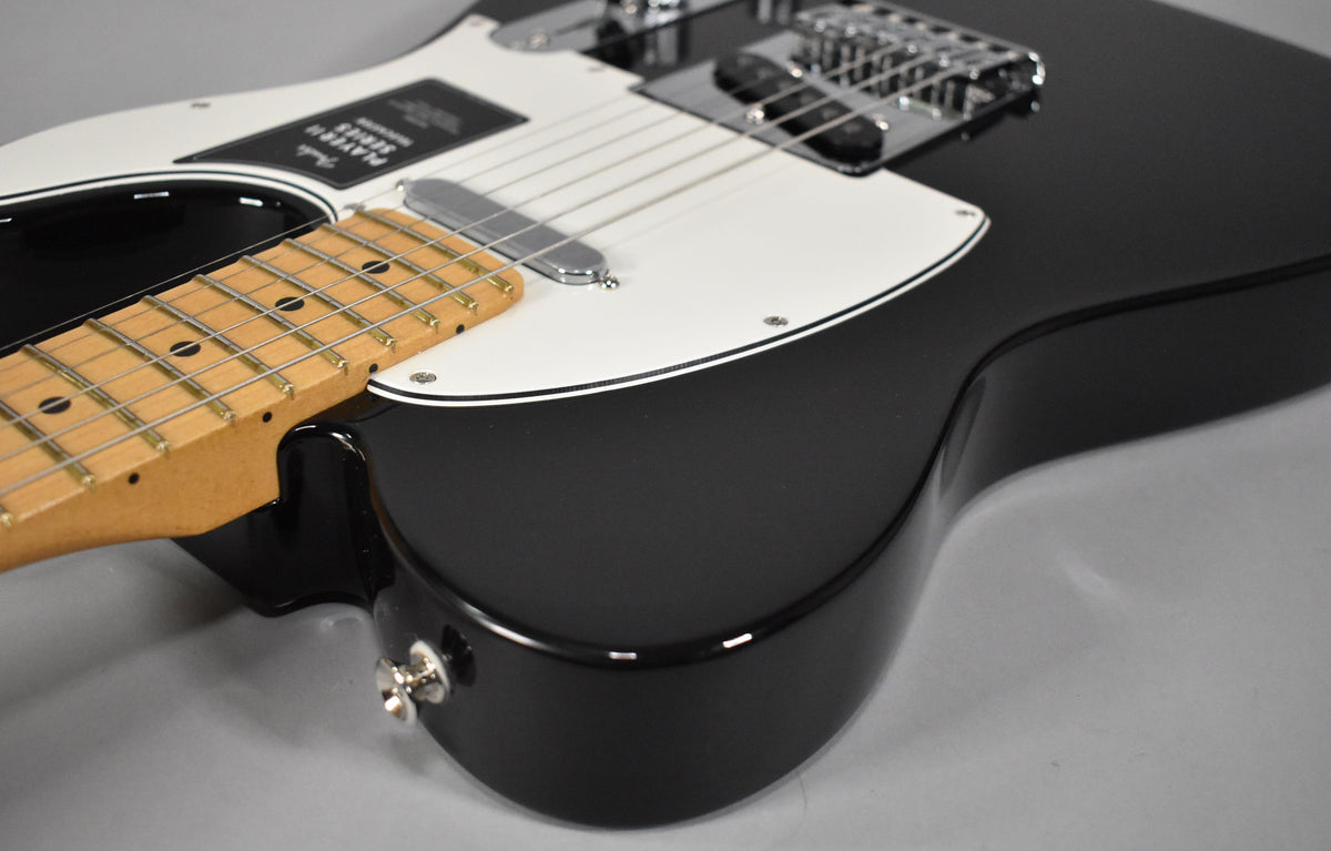 The black Telecaster body with a white pickguard and chrome hardware is angled, showing the input jack and a maple fretboard.
