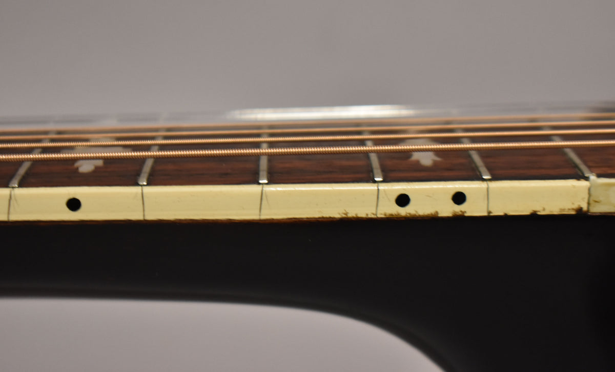 Close-up of the guitar's dark fretboard and light binding, showing wear and side dot markers on the lower frets.