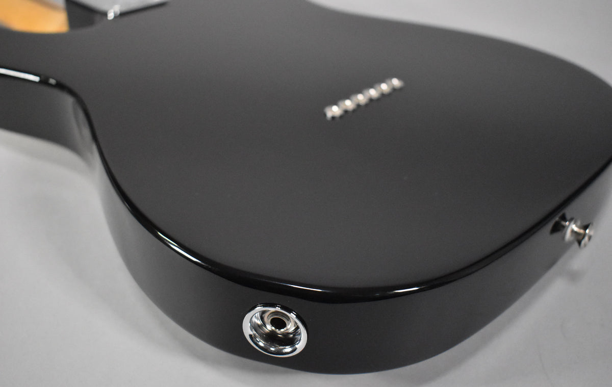 The black Telecaster body, viewed from the rear, shows a chrome output jack on the lower bout and six string ferrules on the back.