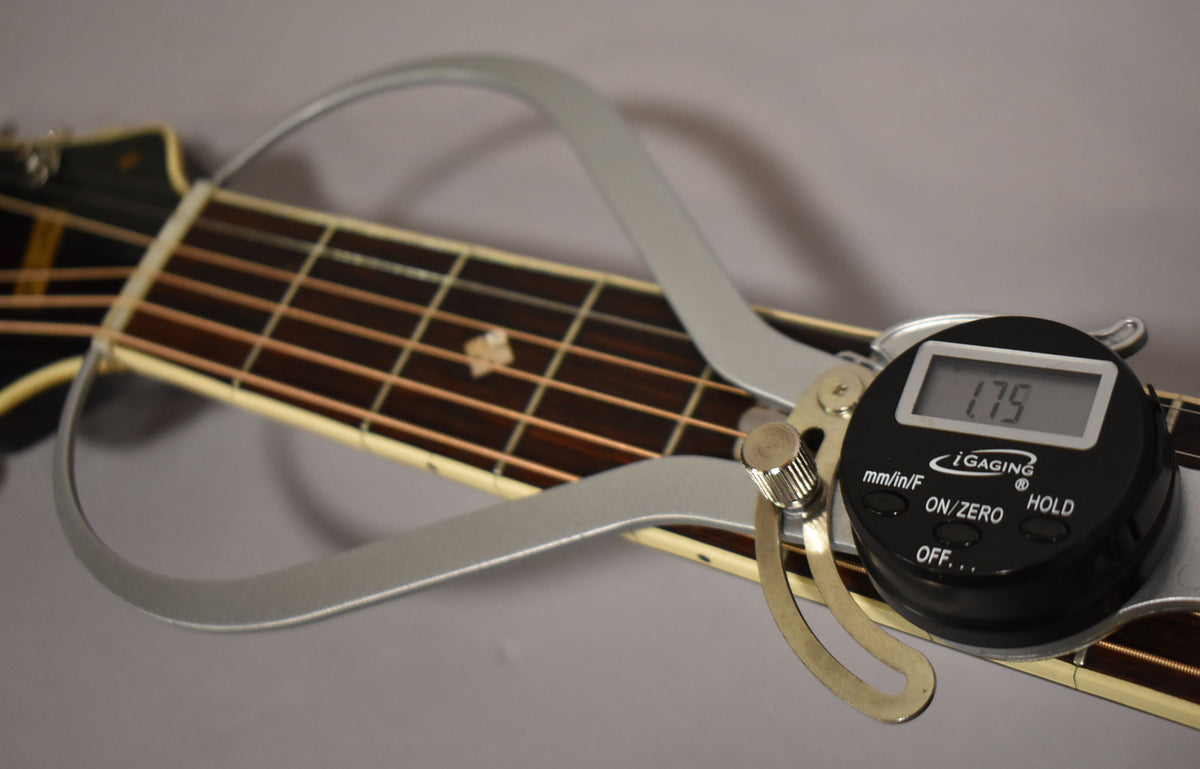A digital caliper measures the nut width of the dark brown fretboard, showing 1.75 inches, with a star inlay at the 7th fret.