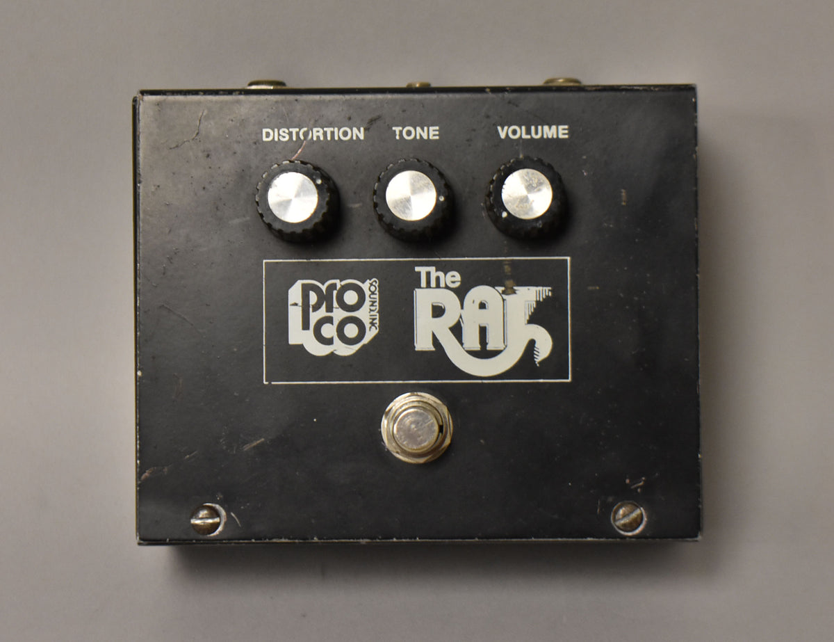 A black rectangular distortion pedal, viewed from above, with three silver-capped black knobs, a silver footswitch, and visible surface wear.