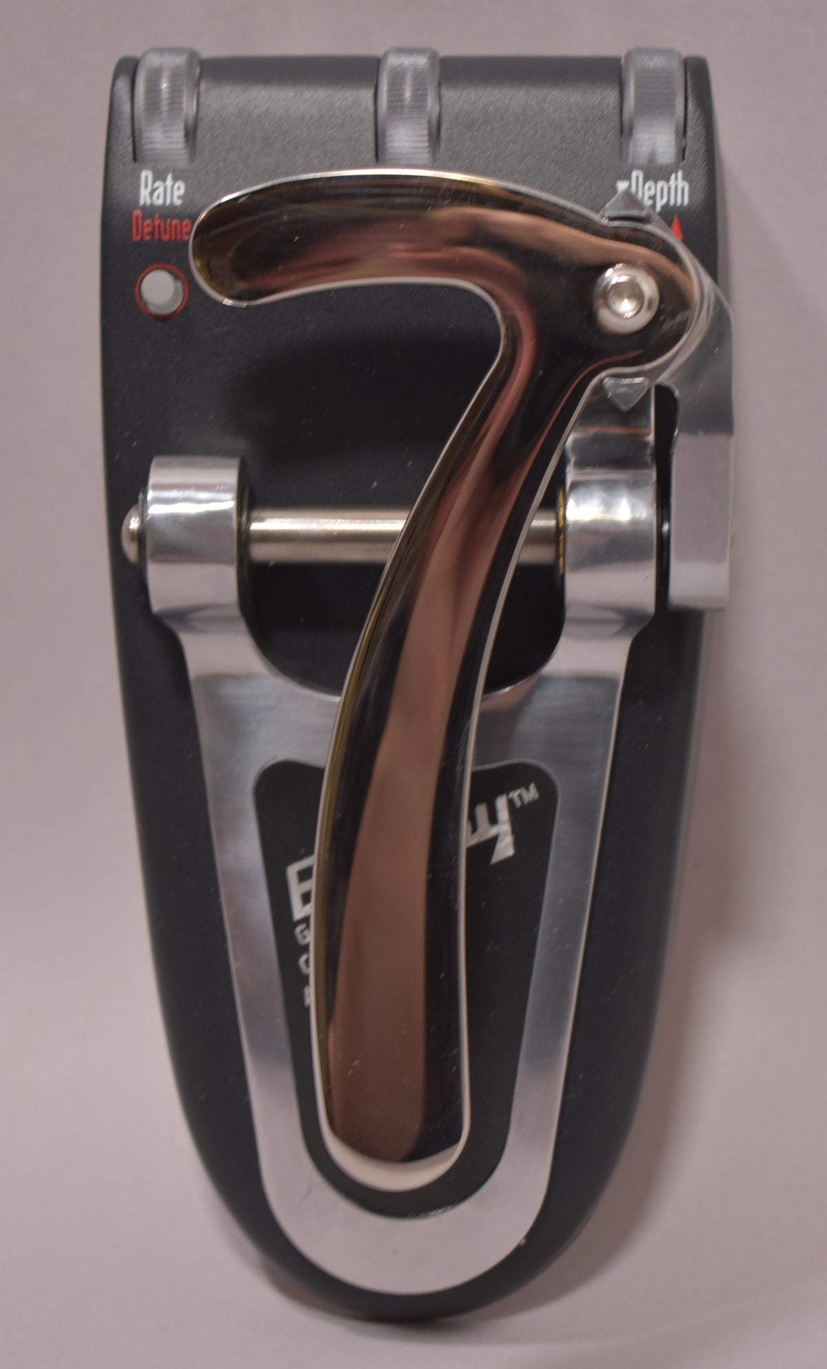 Close-up of the pedal's top, showing the chrome-plated Bigsby-style tremolo arm and two small black control knobs.