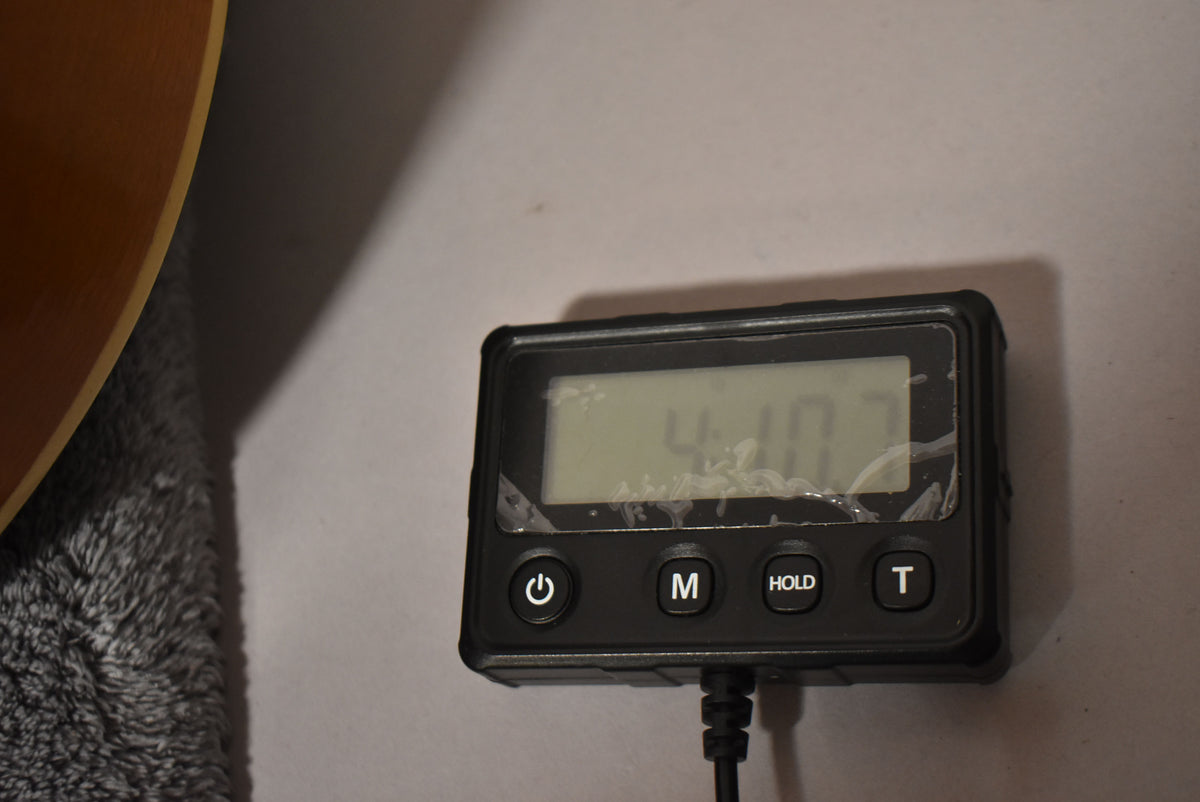 The guitar's light brown body is partially visible on the left, next to a black digital display showing "4:10" with four buttons below.