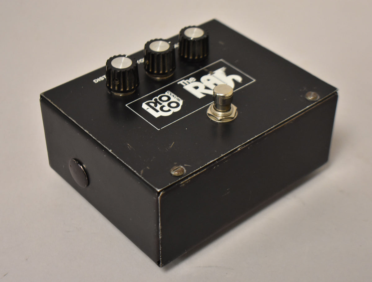 A black rectangular pedal with three black knobs with silver tops, a silver footswitch, and visible scuffs and scratches.