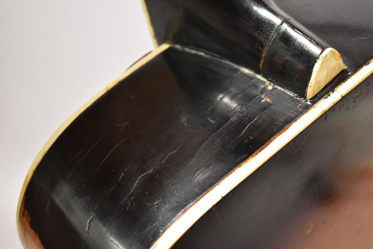 Close-up of the guitar's dark sunburst body and neck joint, showing extensive finish checking and wear along the cream binding.