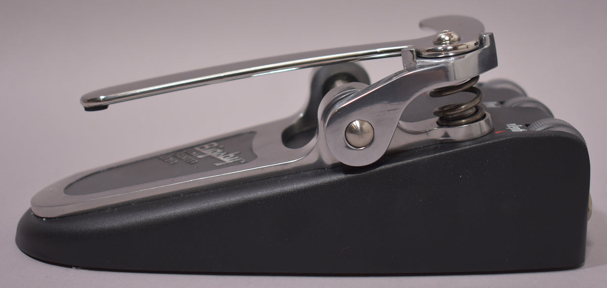 A side view of the black pedal with a shiny chrome Bigsby-style vibrato arm and spring mechanism, showing light wear.