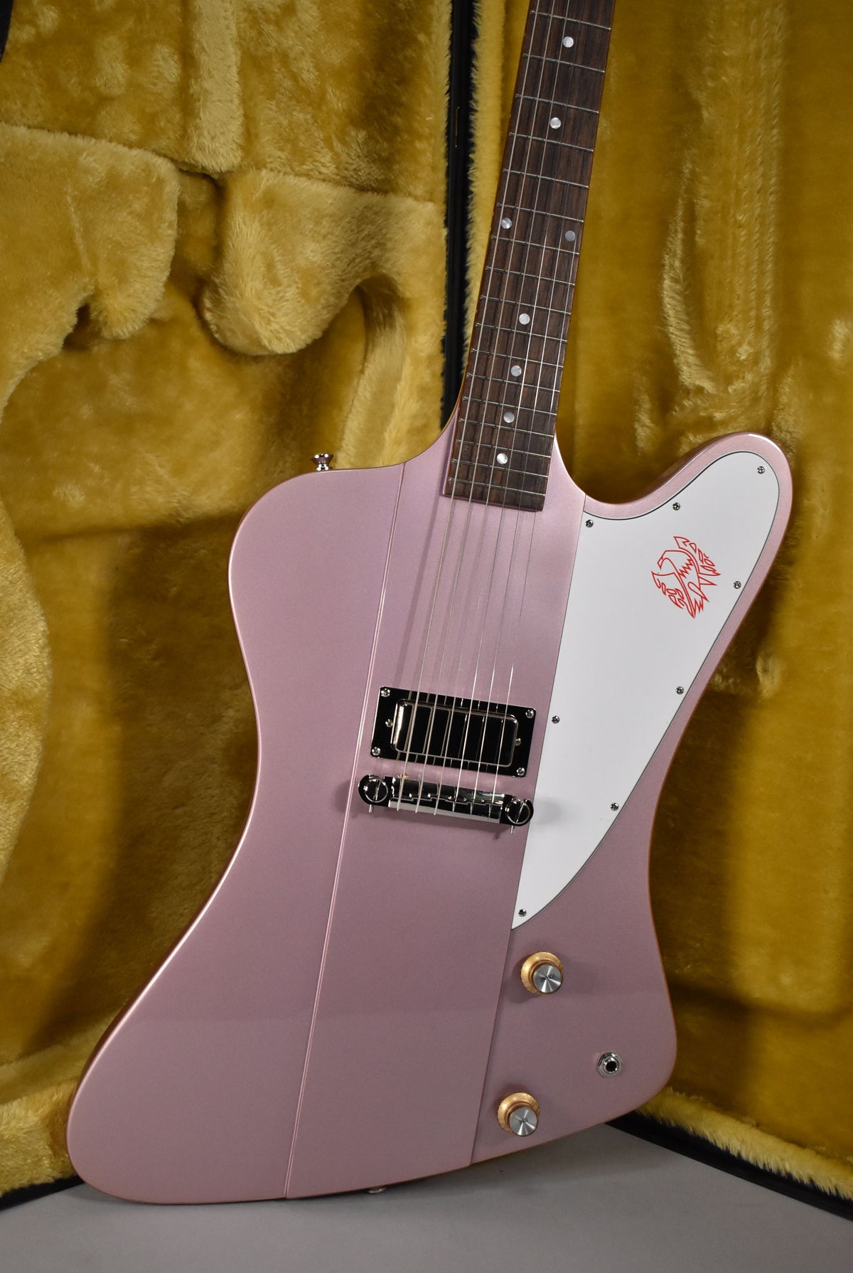 Close-up of the Firebird's heather poly body and neck, showing the single humbucker, white pickguard with red bird graphic, and two gold knobs.